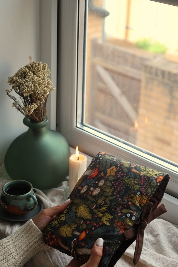 Reader holding book sleeve and preloved mystery book UK forest design.